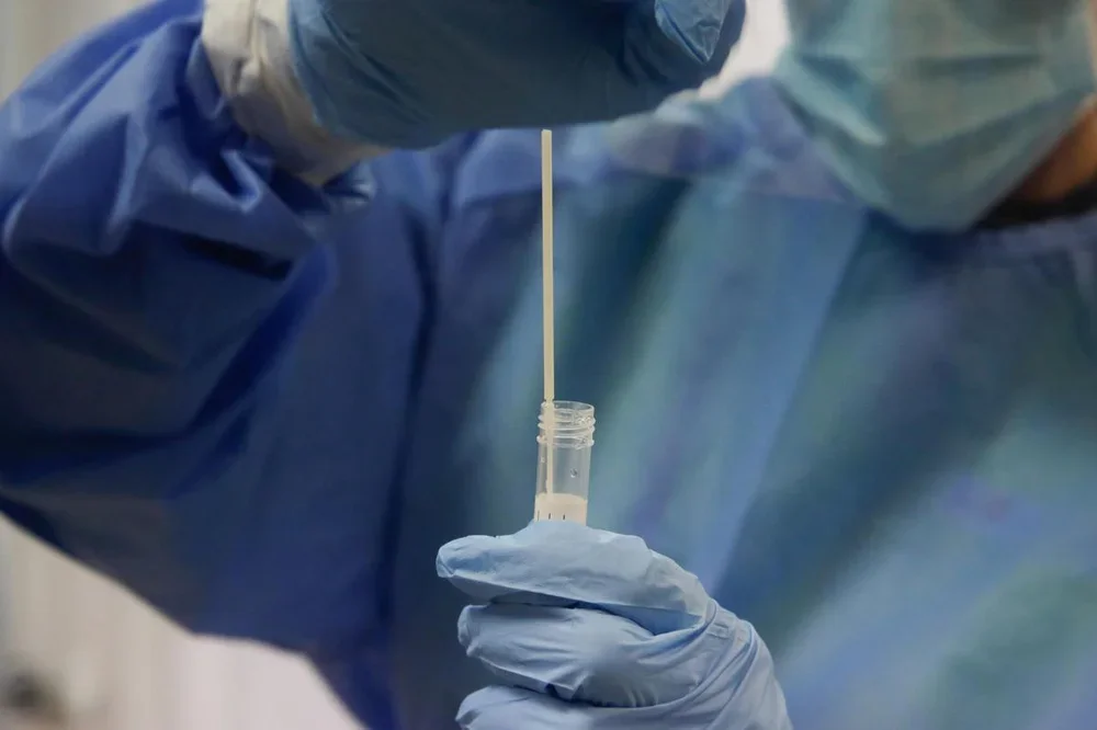Una trabajadora sanitaria con una prueba PCR.
